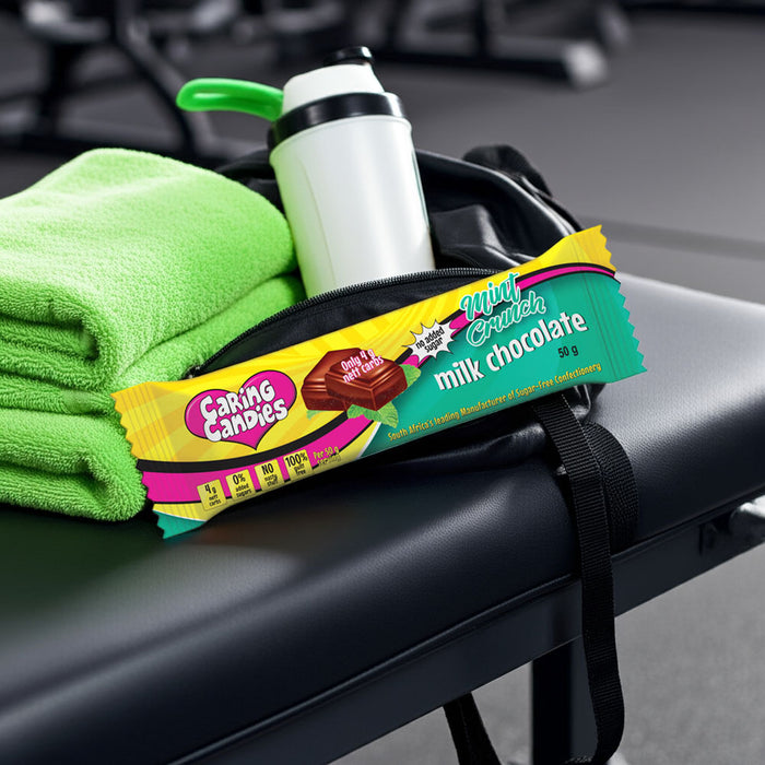 Caring Candies sugar-free mint chocolate bar on a gym seat with green towel and water bottle in the background