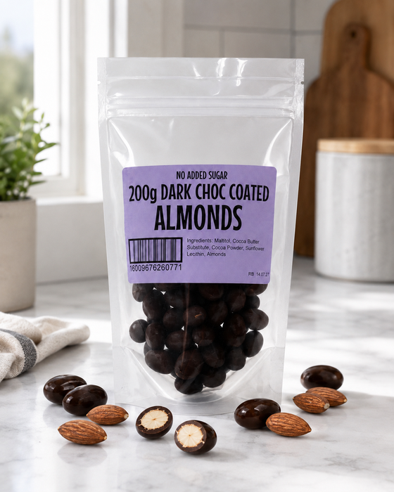 Packaged no added sugar dark chocolate-coated almonds on a marble surface with a kitchen background.