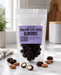 Packaged no added sugar dark chocolate-coated almonds on a marble surface with a kitchen background.