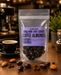 Packaging of no added sugar dark chocolate-coated coffee almonds on a wooden surface with coffee beans and almonds.