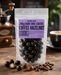 Packaged  no added sugar dark chocolate-coated coffee hazelnuts with a purple label on a wooden surface.