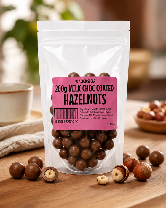 Packaged no added sugar milk chocolate coated hazelnuts with a pink label on a wooden surface.
