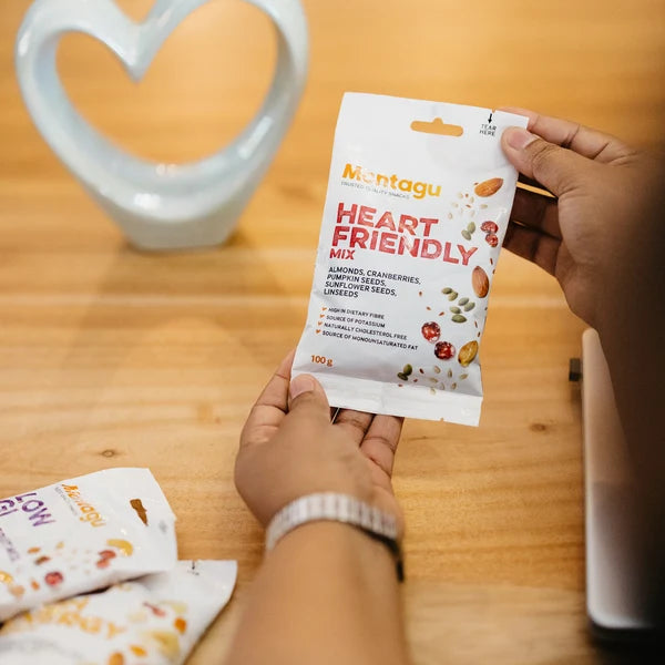 Person holding a Montagu Heart Friendly Mix packet on a wooden table
