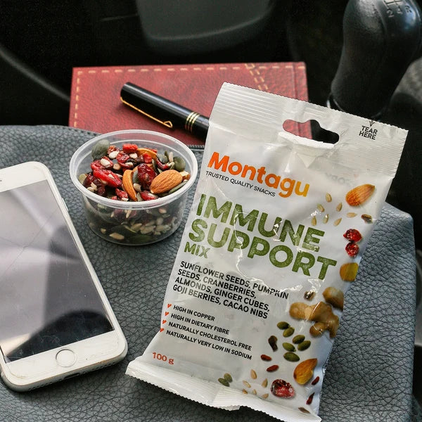 Montagu immune support snack mix packet on a car dashboard with phone and bowl of nuts.