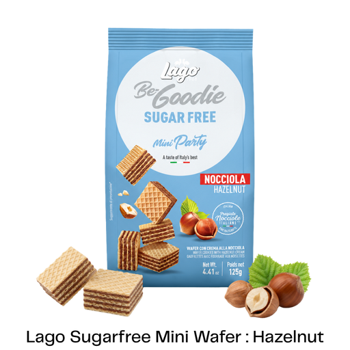A blue bag of Lago Be Goodie Sugar Free Mini Party Nocciola Hazelnut wafers, shown with several hazelnut-filled wafers and hazelnuts arranged around it on a white background with a black text banner at the bottom.