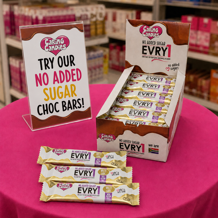 Caring Candies no added sugar chocolate bars displayed on a pink table with a promotional sign.