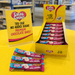 Caring Candies chocolate bars with packaging and promotional signs on a yellow surface.