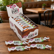Box of Evry1 candy bars on a wooden table with a blurred background