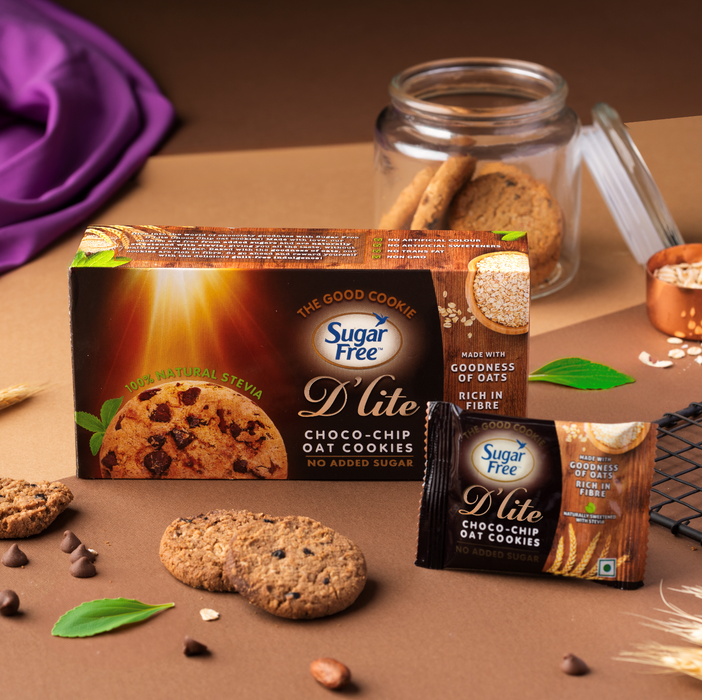 Sugar Free Lite Choco-Chip Oat Cookies in a brown box and an individual packet, styled on a brown surface with cookies, oats, chocolate chips, and green leaves.