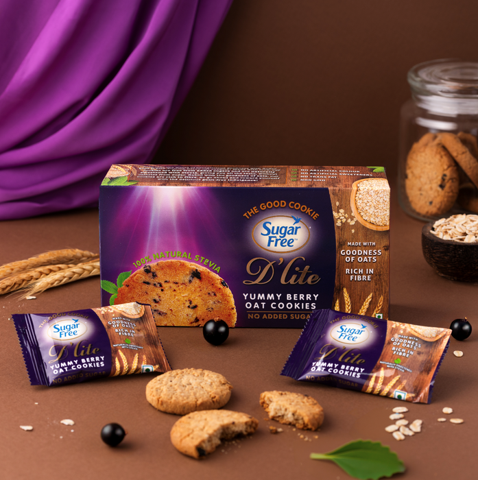Sugar Free D Lite Yummy Berry Oat Cookies in a purple box with three individually wrapped cookies, styled on a dark brown surface with wheat stalks, oats, and a purple fabric drape in the background.