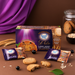 Sugar Free D Lite Yummy Berry Oat Cookies in a purple box with three individually wrapped cookies, styled on a dark brown surface with wheat stalks, oats, and a purple fabric drape in the background.