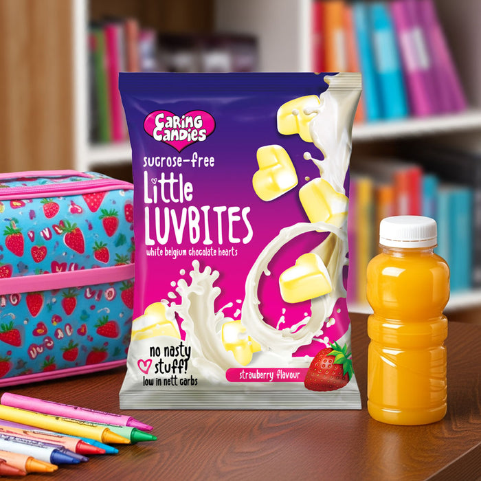 Packet of Caring Candies Little luvbites white chocolate hearts in a strawberry flavour on a kitchen counter with fruits and juice in the background.