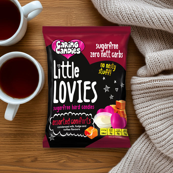 Pack of sugar-free Caring Candies Little Lovies sweets with a cups of tea on a wooden table with a blanket