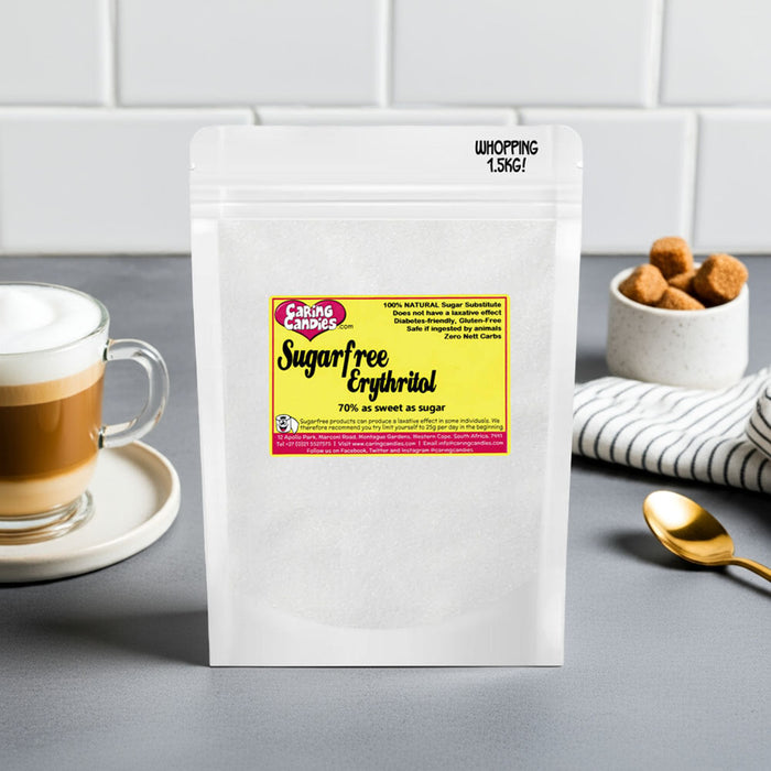 White package of sugar-free erythritol with a yellow label on a gray surface, coffee cup and cookies in the background.