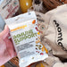A hand holds a bag of Montagu Immune Support Mix in front of other Montagu snack bags and a wicker basket, showing the packaged snack product in a real setting.