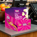 Box of Caring Candies Little Luvbites on a checkout counter with fruits in the background