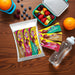 Packaged sugar-free caring candies premium chocolate bars, a fruit container, and a water bottle on a wooden surface.